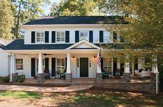 a white house with black shutters and an american flag on the front door is shown