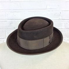 Size 6 7/8 Vintage 1950s 1960s Adam Hats Carbon Brown Porkpie Fedora Hat For your consideration we have a vintage fedora from the ‘50s/‘60s. Made by Adam Hats from a “carbon brown” fur felt, this “Rugby” model features a telescopic crown, brown grosgrain band and edge, leather sweatband, and rayon lining. There are a few spots on the hat band and a few stitches have come out of the leather sweatband. This is still a great hat and wonderful for anyone into slick bop midcentury style.Measurements; Classic Brown Flat Bill Hat, Fitted Brown Top Hat With Flat Brim, Brown Fitted Top Hat With Flat Brim, Brown Flat Bill Hat Bands For Kentucky Derby, Brown Felt Hat With Flat Bill For Formal Occasions, Formal Brown Felt Hat With Flat Bill, Fitted Brown Brimmed Top Hat, Fitted Brown Top Hat With Short Brim, Brown Flat Bill Felt Hat For Kentucky Derby