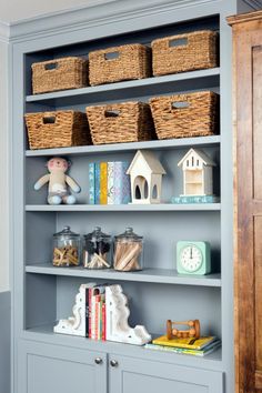 a blue bookcase with baskets and toys on it