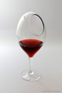 a glass filled with red wine sitting on top of a table