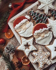 christmas cookies decorated with icing and decorations on a wooden table next to fir branches