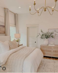 a bedroom with a bed, dresser and chandelier hanging from it's ceiling