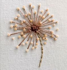 a close up of a flower made out of beads on a piece of cloth with thread