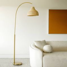 a living room with a white couch and a gold floor lamp