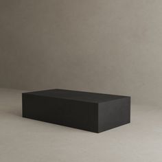 a black rectangular object sitting on top of a white floor next to a gray wall