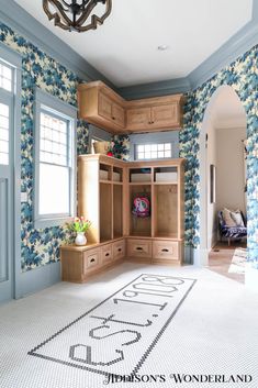 a room with blue and white wallpaper, wooden cabinets and a chandelier