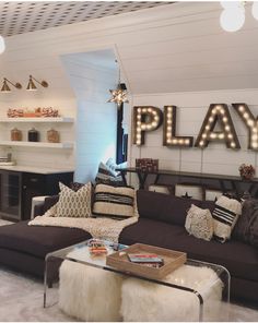 a living room filled with lots of furniture and lights on the wall next to it