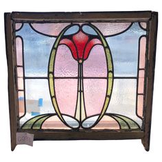 an old stained glass window with a flower on the bottom and side panel, in brown frame