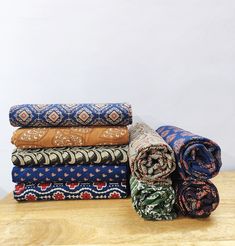 a stack of different colored blankets on top of a wooden table