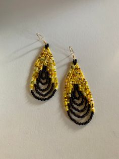 These are a great bright set of earrings that have a fun yellow bead mix that are well balanced out by the dark brown swag at the bottom. Yellow Hoop Earrings With Dangling Beads, Yellow Gold Beads Drop Earrings, Yellow Gold Beaded Drop Earrings, Yellow Beaded Earrings With Black Beads, Yellow Beaded Teardrop Earrings, Yellow Teardrop Beaded Earrings With Colorful Beads, Yellow Teardrop Beaded Earrings With Dangling Beads, Yellow Dangle Hoop Earrings With Ear Wire, Yellow Teardrop Earrings With Dangling Beads