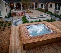 a hot tub sitting on top of a wooden deck in front of a house with steps leading to it