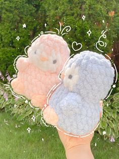 two small stuffed animals sitting on top of each other in front of some bushes and trees