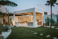 a modern house with an outdoor kitchen and living area in the back yard at dusk