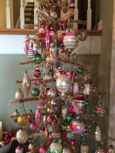 a christmas tree with ornaments hanging from it's branches in front of a staircase