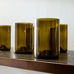 three green vases sitting on top of a wooden shelf