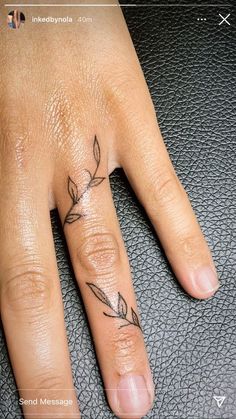 a person's hand with a small tattoo on the middle finger and an arrow