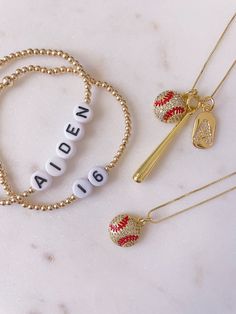 three necklaces with letters and charms on them sitting next to each other in front of a marble surface