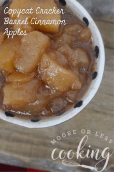 a bowl filled with caramel apple crisp on top of a wooden table next to a spoon