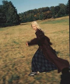 a woman in a long dress running through a field