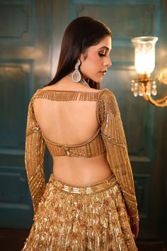 Ombre gold and silver bridal lehenga embellished with sequin, crystals, beads, cutdana embroidery, and a matching full-sleeved blouse in gold. The lehenga comes with a shaded embroidered cutwork dupatta.DELIVERY TIMEPlease allow 8-12 weeks for your outfit to arrive.FABRIC DETAILSNetProfessional cleaning only. Golden Lehenga Blouse Designs, Gold Designer Wear Lehenga With Traditional Drape, Bollywood Sequin Blouse Piece For Wedding, Gold Bollywood Designer Lehenga, Gold Embellished Choli, Bollywood Style Blouse Piece With Sequins For Wedding, Bollywood Style Designer Gold Lehenga, Embellished Gold Choli, Gold Sharara With Sequins In Traditional Drape