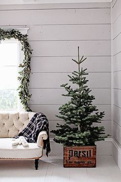 a living room with a couch, christmas tree and window in the corner next to it