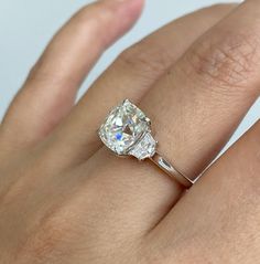 a woman's hand with a diamond ring on top of her finger and an engagement band