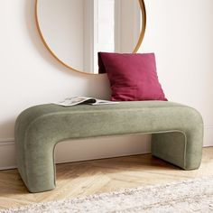 a green bench sitting in front of a round mirror