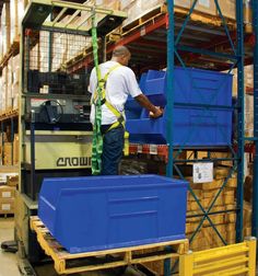 a man standing on a pallet in a warehouse next to blue bins and boxes