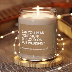 a candle that is sitting on a table with some string lights around it and the words can you read some stuff out loud on our wedding?