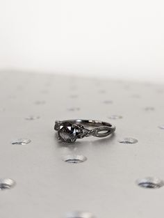 a diamond ring sitting on top of a silver surface with drops of water around it