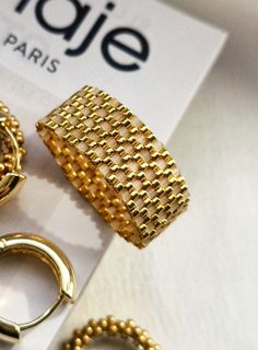 three pairs of gold colored rings and bracelets sitting on top of a white box