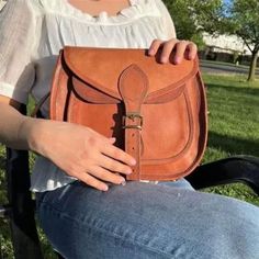 Rustic Goat Leather Crossbody Satchel Bag on model's lap Handmade Crossbody Shoulder Bag For On-the-go, Gift Leather Strap Crossbody Shoulder Bag, Gift Crossbody Shoulder Bag With Leather Strap, Brown Leather Satchel Shoulder Bag With Leather Strap, Brown Leather Strap Crossbody Saddle Bag, Daily Use Crossbody Saddle Bag With Leather Strap, Leather Strap Crossbody Bag For Gift, Natural Satchel Shoulder Bag For Everyday Use, Natural Leather Satchel Shoulder Bag