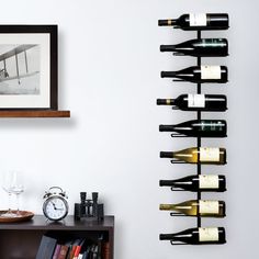 a wall mounted wine rack with several bottles on it and a clock next to it