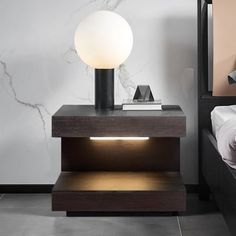 a night stand with a lamp on it next to a bed