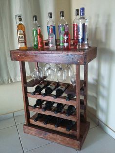 a wooden wine rack filled with lots of bottles and glasses on top of a tiled floor