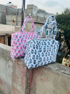 two bags sitting on top of a cement wall