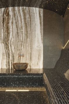 a bowl sitting on top of a tiled floor next to a wall covered in marble