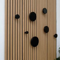 the wall is made out of wood and has black knobs on each one side