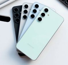 three cell phones sitting next to each other on top of a white table with keyboard and mouse