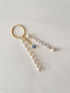 two key chains with beads hanging from them on a white surface, one has an evil eye and the other is beaded