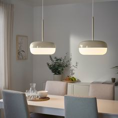 a dining room table with four chairs and two pendant lights hanging over it's head