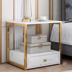 a white and gold side table with two drawers on each side, next to a bed