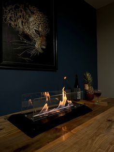 there is a fire place on the table in the room with two wine glasses and a painting