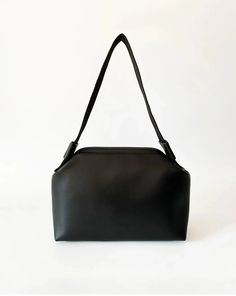 Introducing our elegant black faux leather handbag, a stylish accessory that combines sophistication with practicality. Measuring 28 cm in width, 19 cm in height, and 10 cm in depth, this handbag offers the ideal space for daily use, allowing you to carry your belongings comfortably. The interior is lined with faux leather, ensuring your items are safely stored and organized neatly. An inside pocket provides a dedicated space for smaller items, making them easy to find and keep orderly. One of t Minimalist Black Baguette Bag For Everyday, Minimalist Black Everyday Baguette Bag, Black Baguette Bag With Large Capacity For Everyday Use, Black Large Capacity Baguette Bag For Everyday Use, Black Handheld Baguette Bag For Daily Use, Black Square Baguette Bag With Detachable Strap, Evening Faux Leather Baguette Bag With Removable Pouch, Faux Leather Box Shoulder Bag With Removable Pouch, Black Leather Box Bag With Double Handle