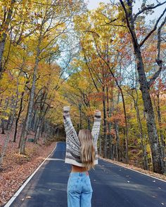 a woman standing on the road with her arms in the air