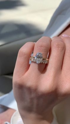 a woman's hand holding a diamond ring in her left hand, with the other hand on top of it