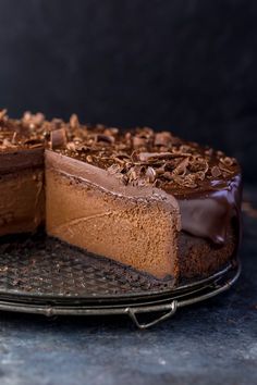 a chocolate cheesecake with one slice cut out on a cake plate and another piece missing from it