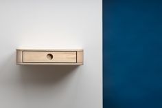 a wooden shelf with a hole in the middle next to a blue and white wall