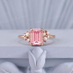 a pink tourmaline ring with pearls on the sides and an oval cut diamond in the center