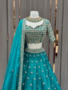 Teal green lehenga beautified in flora gold zari embroidery with sequin, aari tari, cut dana and pearl work all over. Completed look with similarly embroidered cut work blouse with lace border work dupatta. Embrace the whims of rich heritage by adorning this Teal green lehenga. Fabric: Raw Silk Size: 38/M Occasion: Wedding Ceremony or Reception WASH CARE INSTRUCTIONS - Please Dry clean only when it is applicable. Slight color variation is possible due to digital photography. Ready to Ship! Green Chanderi Set For Reception, Green Sets With Zari Work For Reception, Green Raw Silk Sharara With Dori Work, Green Raw Silk Anarkali Set For Reception, Designer Green Lehenga With Traditional Drape, Green Lehenga With Traditional Drape For Designer Wear, Pista Green Designer Choli With Traditional Drape, Pista Green Designer Wear Choli With Traditional Drape, Green Lehenga For Reception